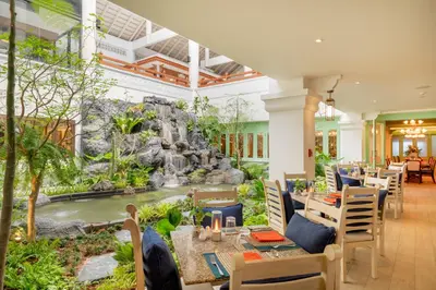 a restaurant with a waterfall in the middle of the room at Thavorn Palm Beach Resort Phuket in Karon Beach