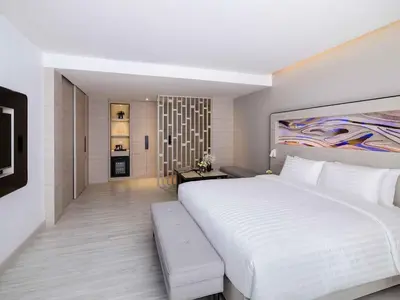 a bedroom with a large white bed and a living room at Novotel Phuket City Phokeethra in Phuket Town