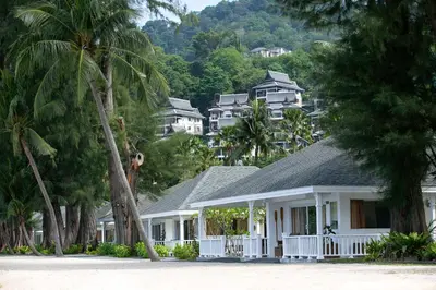 a white house with palm trees and houses at Thavorn Beach Village Resort & Spa Phuket in Kamala Beach