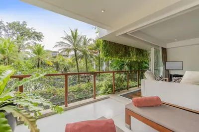a room with a balcony with a couch and a television at The Chava Resort in Surin Beach