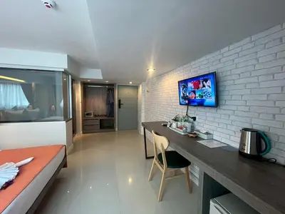 a bedroom with a desk and a bed in a room at MORE Patong Hotel in Patong Beach
