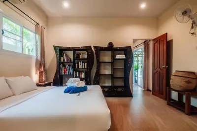 a bedroom with a white bed and a book shelf at Chaba Pool Villa Private Tropical Villa With Pool in Nai Harn Beach