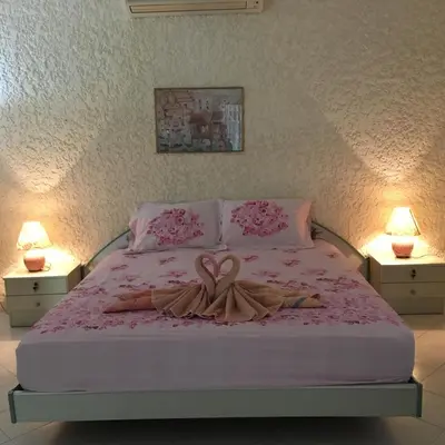 a bedroom with a bed with a pink blanket and two lamps at Peaceful homestay in Rawai Beach