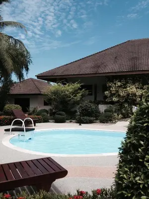 a swimming pool with a bench next to a house at Peaceful homestay in Rawai Beach