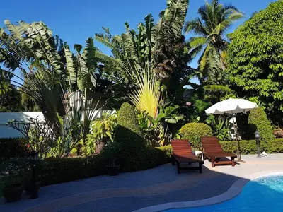 two chairs and an umbrella next to a swimming pool at Peaceful homestay in Rawai Beach