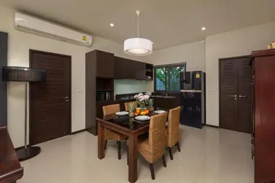 a kitchen with a wooden table with chairs and a dining room at VILLA FLORES 3BR Private Pool 10 min to Nai Harn in Rawai Beach