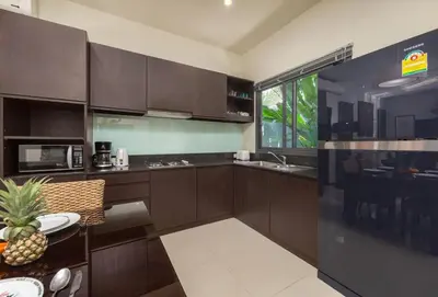 a kitchen with brown cabinets and a table with a pineapple at VILLA FLORES 3BR Private Pool 10 min to Nai Harn in Rawai Beach