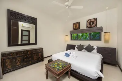 a bedroom with a bed with a table and a mirror at VILLA FLORES 3BR Private Pool 10 min to Nai Harn in Rawai Beach