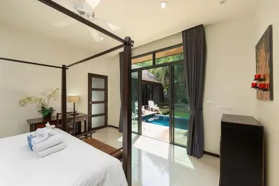 a bedroom with a bed and a view of a pool at VILLA FLORES 3BR Private Pool 10 min to Nai Harn in Rawai Beach