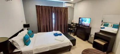 a hotel room with a bed and a desk and a television at Cafe de Paris in Patong Beach