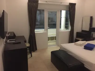 a bedroom with a bed and a desk and a window at Cafe de Paris in Patong Beach