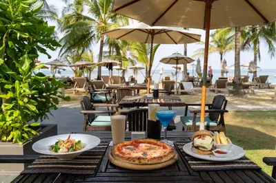 a table with a pizza and a plate of food at Cape Panwa Hotel Phuket in Panwa Beach