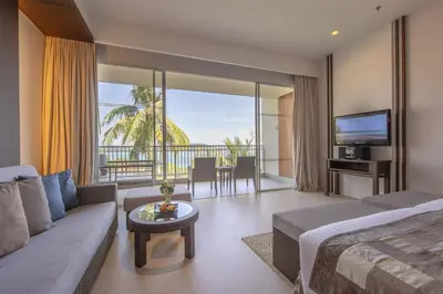 a hotel room with a bed and a couch and a television at Cape Panwa Hotel Phuket in Panwa Beach