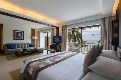 a bedroom with a large bed and a view of the ocean at Cape Panwa Hotel Phuket in Panwa Beach
