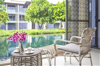a patio with two chairs and a table with flowers at Luxury Oceanfront_pool access apartment in Mai Khao Beach