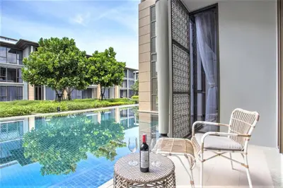 a patio with a table and chairs next to a swimming pool at Luxury Oceanfront_pool access apartment in Mai Khao Beach