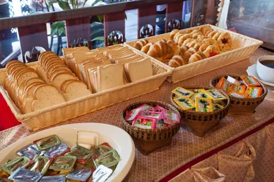 a table with baskets of bread and baskets of pastries at Royal Phawadee Village Patong - 2 Minutes walk to the beach in Patong Beach