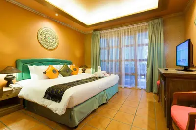 a bedroom with a large bed and a television at Royal Phawadee Village Patong - 2 Minutes walk to the beach in Patong Beach
