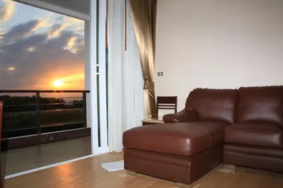 a brown leather couch in a living room with a window at Sea and Sky Condominium Room #406 in Karon Beach