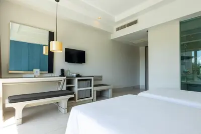 a white bedroom with a bed and a tv at Navinda Krabi in Ao Nang Beach
