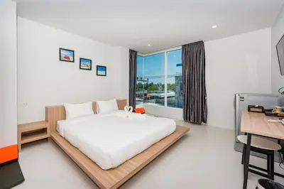 a bedroom with a bed and a desk and a window at Phuket Marine Poshtel - SHA Plus in Chalong