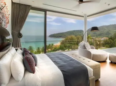 a bedroom with a large bed and a view of the ocean at Malaiwana Residences in Nai Thon Beach