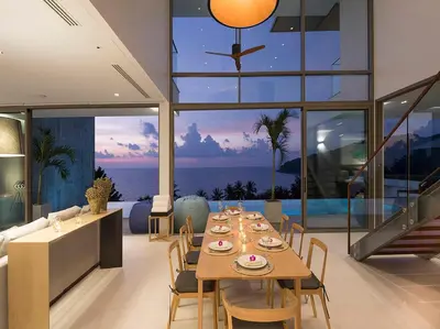 a dining room with a table and a view of the ocean at Malaiwana Residences in Nai Thon Beach
