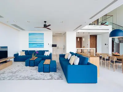 a living room with blue couches and a dining room at Malaiwana Residences in Nai Thon Beach