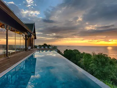 a swimming pool in front of a house with a sunset at Malaiwana Villas in Nai Thon Beach