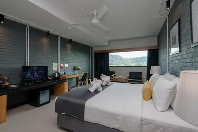 a bedroom with a bed and a desk and a television at DARA Hotel in Phuket Town