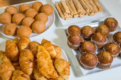 a table topped with plates of pastries and muffins at Aonang All Seasons Beach Resort in Ao Nang Beach