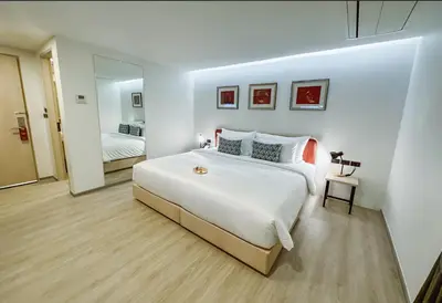a bedroom with a large white bed and a mirror at Hotel Midtown Ratsada in Phuket Town