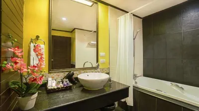 a bathroom with a sink and a mirror and a tub at Aonang Orchid Resort in Ao Nang Beach