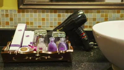 a hair drier and glass bottles on a holder next to a toilet at Aonang Orchid Resort in Ao Nang Beach