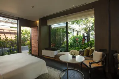 a bedroom with a bed and a table and a window at Rosewood Phuket in Patong Beach