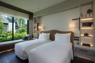 two beds in a bedroom with a large window at Rosewood Phuket in Patong Beach