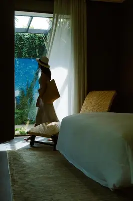 a woman walking out of a window in a bedroom at Rosewood Phuket in Patong Beach