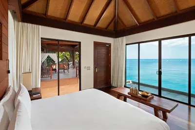 a bedroom with a bed and a view of the ocean at Paresa Resort Phuket in Kamala Beach