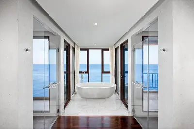 a bathroom with a tub and a view of the ocean at Paresa Resort Phuket in Kamala Beach