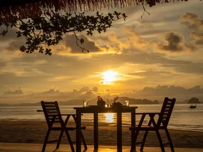 a table on the beach with the sunset in the background at Tup Kaek Sunset Beach Resort-SHA Plus in Tab Kaek Beach