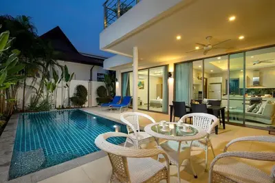 a villa with a swimming pool with chairs and a table at VILLA RAJA 4BR Private pool villa in Rawai Beach