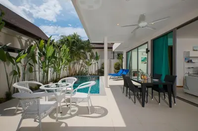 a patio with a table and chairs and a pool at VILLA RAJA 4BR Private pool villa in Rawai Beach