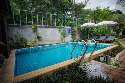 a swimming pool with chairs and umbrellas in a yard at Capricorn Village - SHA Extra Plus in Patong Beach