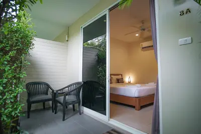 a patio with two chairs and a bed in a room at Capricorn Village - SHA Extra Plus in Patong Beach
