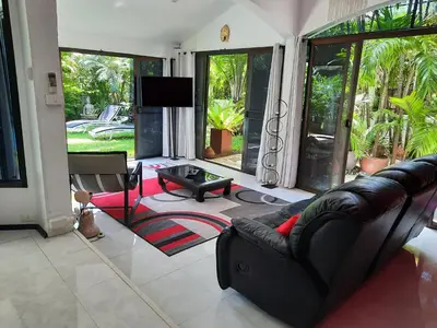 a living room with a couch and a tv at Bjou, Cosy Tropical Villa in Rawai Beach