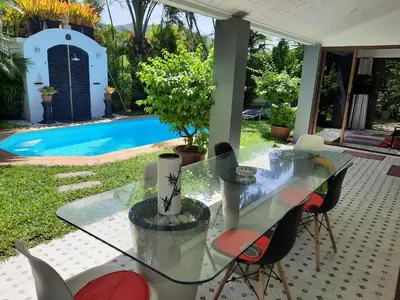 a glass table and chairs in front of a pool at Bjou, Cosy Tropical Villa in Rawai Beach