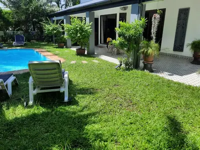a lawn chair sitting in the grass next to a house at Bjou, Cosy Tropical Villa in Rawai Beach