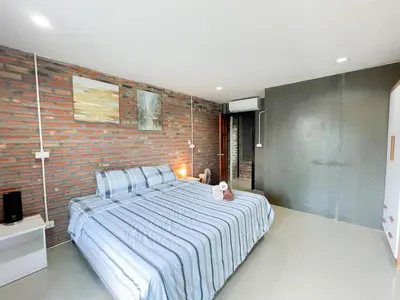 a bedroom with a bed and a brick wall at The Endless Bangtao Residence LOFT 9 in Bang Tao Beach