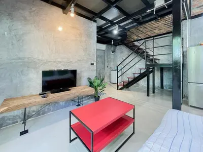 a living room with a red table and a tv at The Endless Bangtao Residence LOFT 9 in Bang Tao Beach