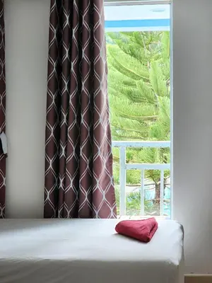 a bed with a red pillow in front of a window at The Palace Aonang Resort in Ao Nang Beach